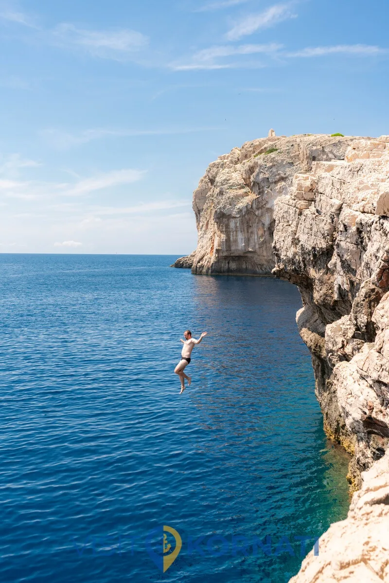 Guest jumping into the clear sea below the cliffs of Mana